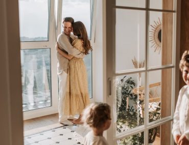 A joyful family moment with parents and children cuddling indoors during the day.
