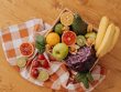 A vibrant flat lay of assorted fresh fruits on a checkered cloth over a wooden surface, perfect for healthy lifestyle concepts.